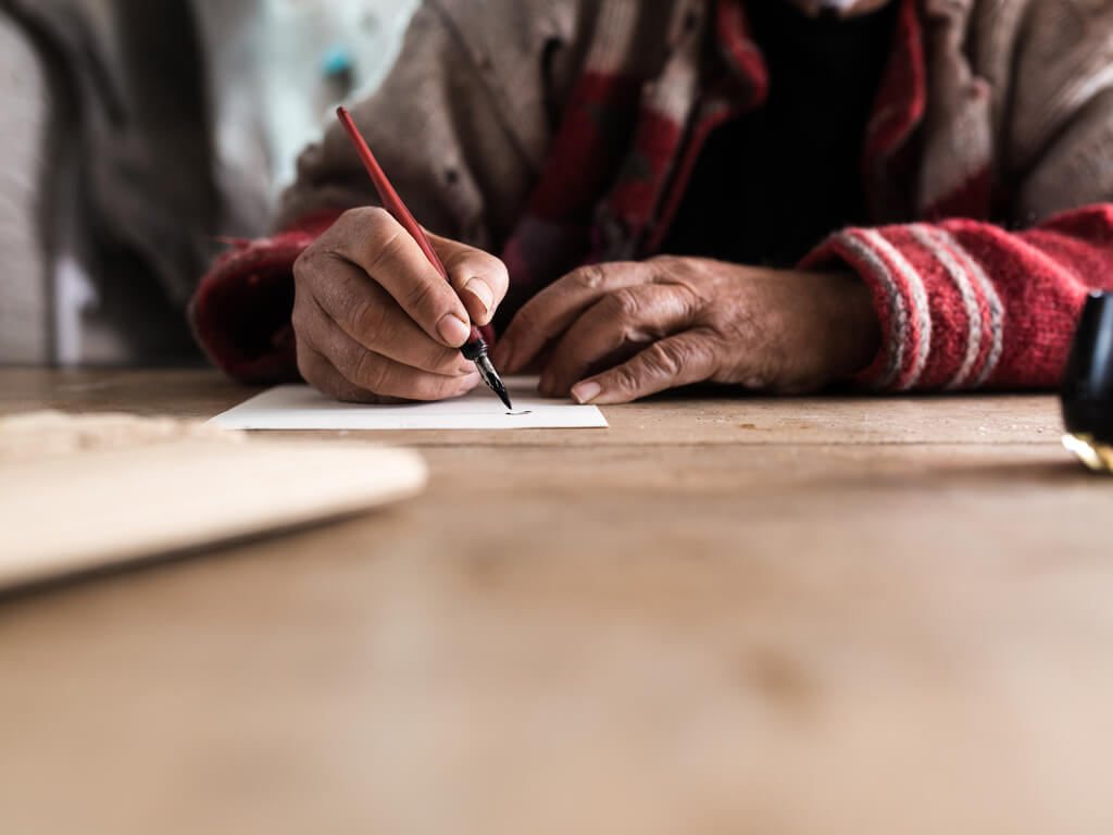 elderly person writing on paper