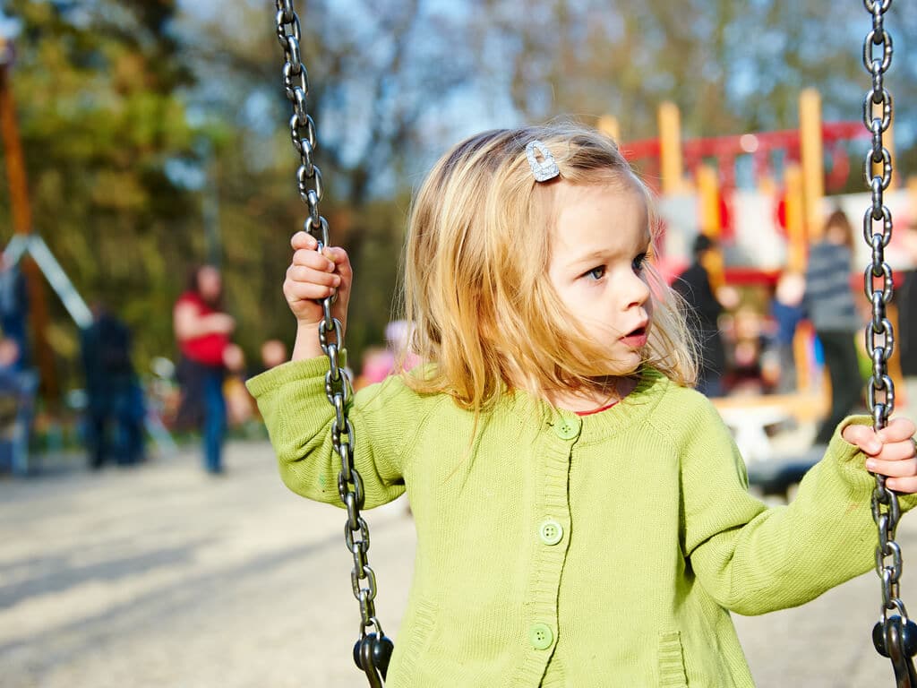 little girl swinging on a park swing